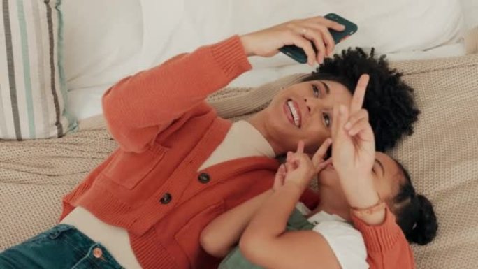 自拍、家庭和社交媒体上，一名黑人妇女和女孩在家里的卧室里摆姿势拍照。与母亲和女儿一起在床上合影的移动