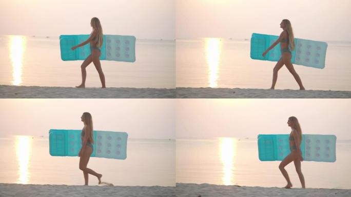 幸福的肖像27岁的拉丁美洲和西班牙裔年轻女子穿着绿色比基尼，在热带海滩上背着蓝色充气床垫，沿着日落的