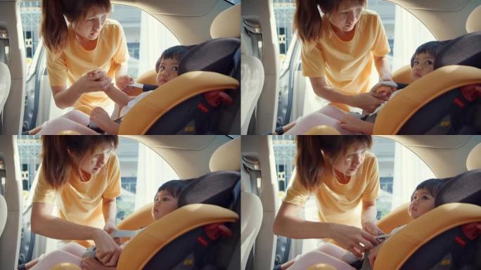 快乐快乐的亚洲家庭妈妈在和蹒跚学步的女孩准备乘车旅行之前，系好儿童汽车座椅的安全带。