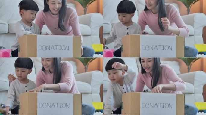 快乐的亚洲母亲教小男孩关于可持续性的儿子如何在家里将玩具包装到捐赠盒中，教/学习捐赠概念。
