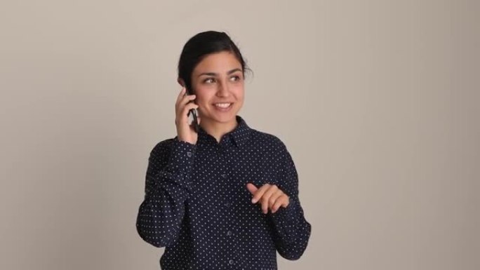 兴奋的年轻印度女子拿着手机交谈。