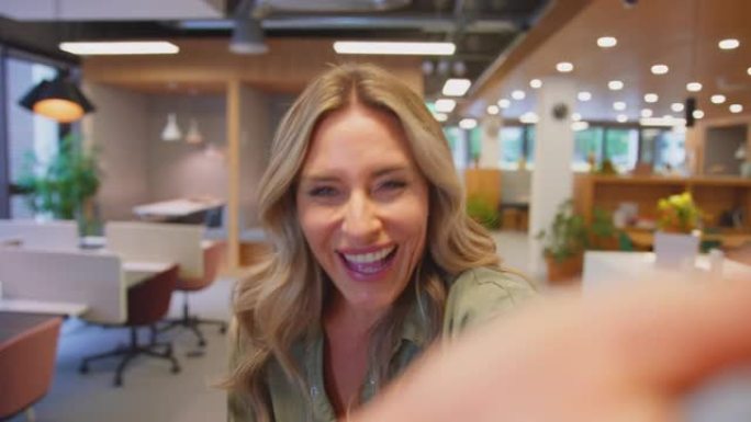 成熟女商人走过现代办公室的POV自拍肖像在手机上对着相机说话-慢动作拍摄