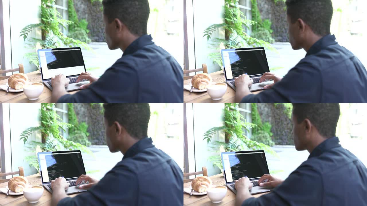 年轻人忙于在咖啡店的笔记本电脑上工作