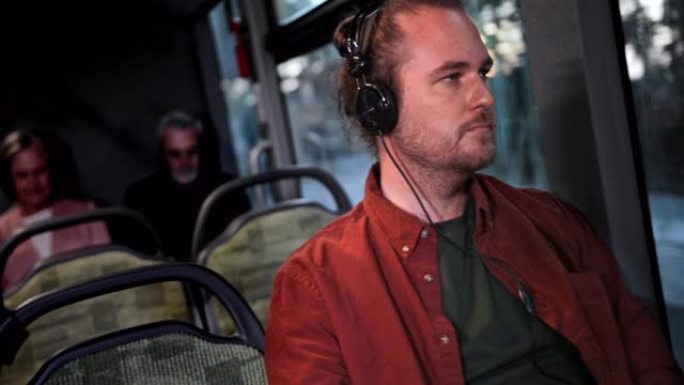 坐在公共巴士内的男子在耳机上听音乐