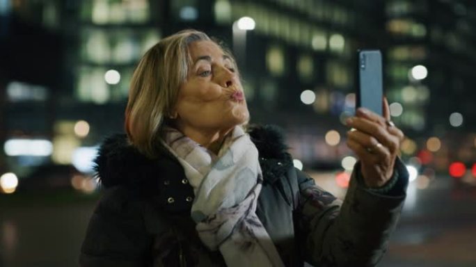 晚上，一位迷人的高级女性正在城市中心用智能手机进行自拍o视频通话。