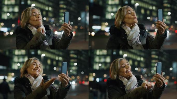 晚上，一位迷人的高级女性正在城市中心用智能手机进行自拍o视频通话。