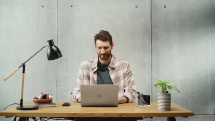 专业的有创造力的人坐在办公室的办公桌前，在笔记本电脑上工作。时尚干净的办公空间设计非常适合生产力、效