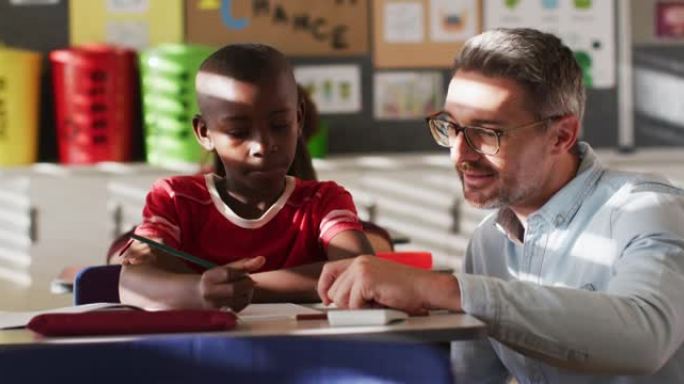 多元化的快乐男老师在学习过程中帮助坐在教室里的男生