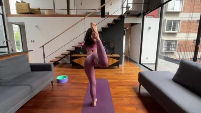 电视上的一堂课后，年轻的健康女性在家练习瑜伽的后视图