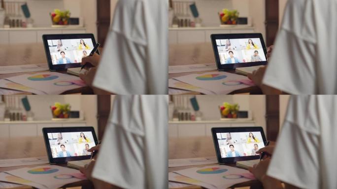亚洲女商人使用数字平板电脑通过视频通话与同事讨论计划头脑风暴在线会议，同时在家厨房远程工作。