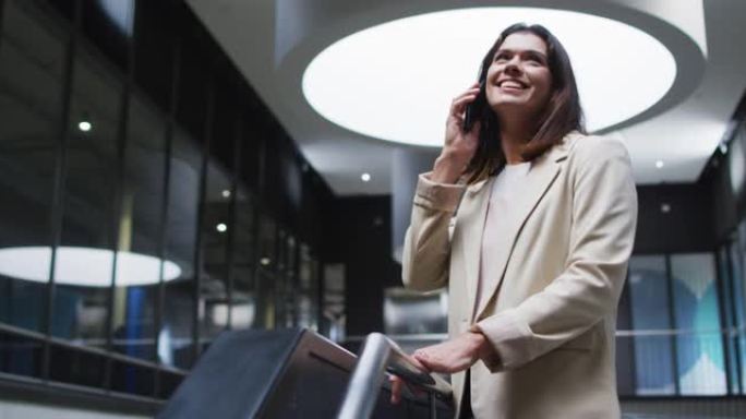 微笑的白人女商人在现代办公室的大厅使用智能手机