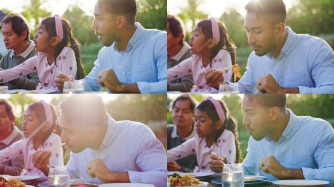 年轻人用筷子和家人一起在外面的桌子上吃中国菜。在活动中与父亲，女儿和其他亲戚共进午餐或晚餐或在户外聚