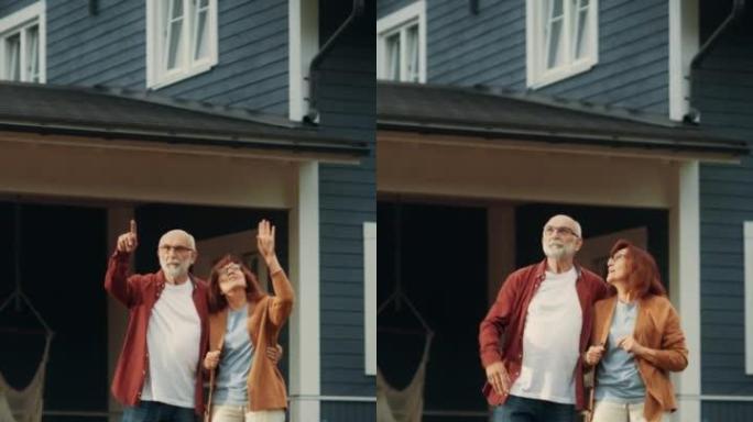 垂直屏幕: 健康的老年夫妇走在他们住宅区的户外，互相拥抱。爱成人，谈心，乐在其中，指向远方，享受他们