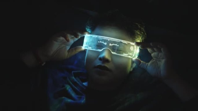 使用虚拟现实眼镜的亚洲女性晚上躺在床上，紫外线赛博朋克眼镜
