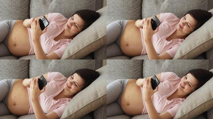 孕妇用智能手机躺在沙发上休息