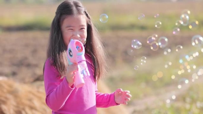 SLO MO微笑着美丽的小女孩在户外玩泡泡玩具