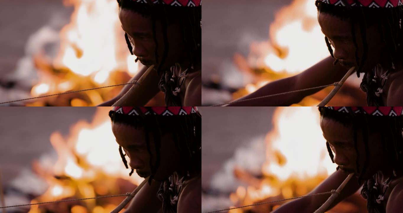 San人 (Bushmen) 在日落时在火旁演奏传统乐器的特写肖像视图