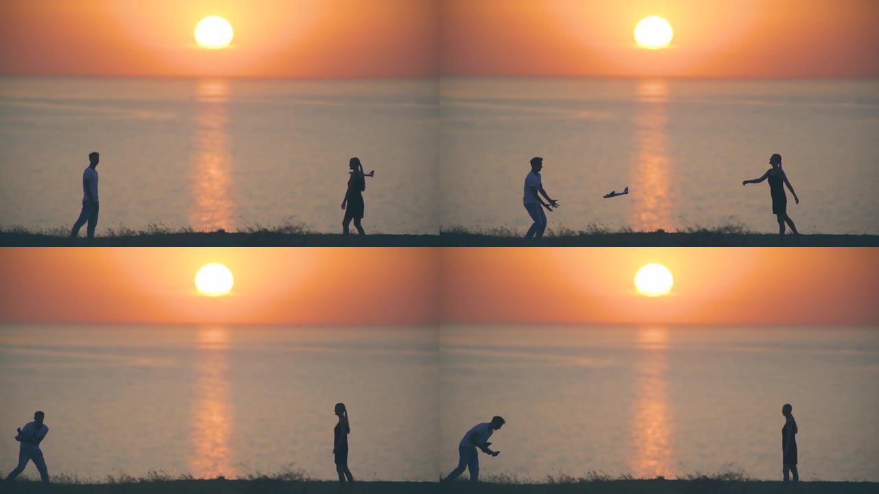 男人和女人把玩具飞机扔在日落背景上
