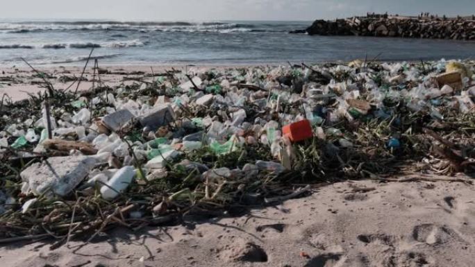 在海滩上冲刷的塑料污染的特写平移视图。对海洋和海洋的环境破坏。