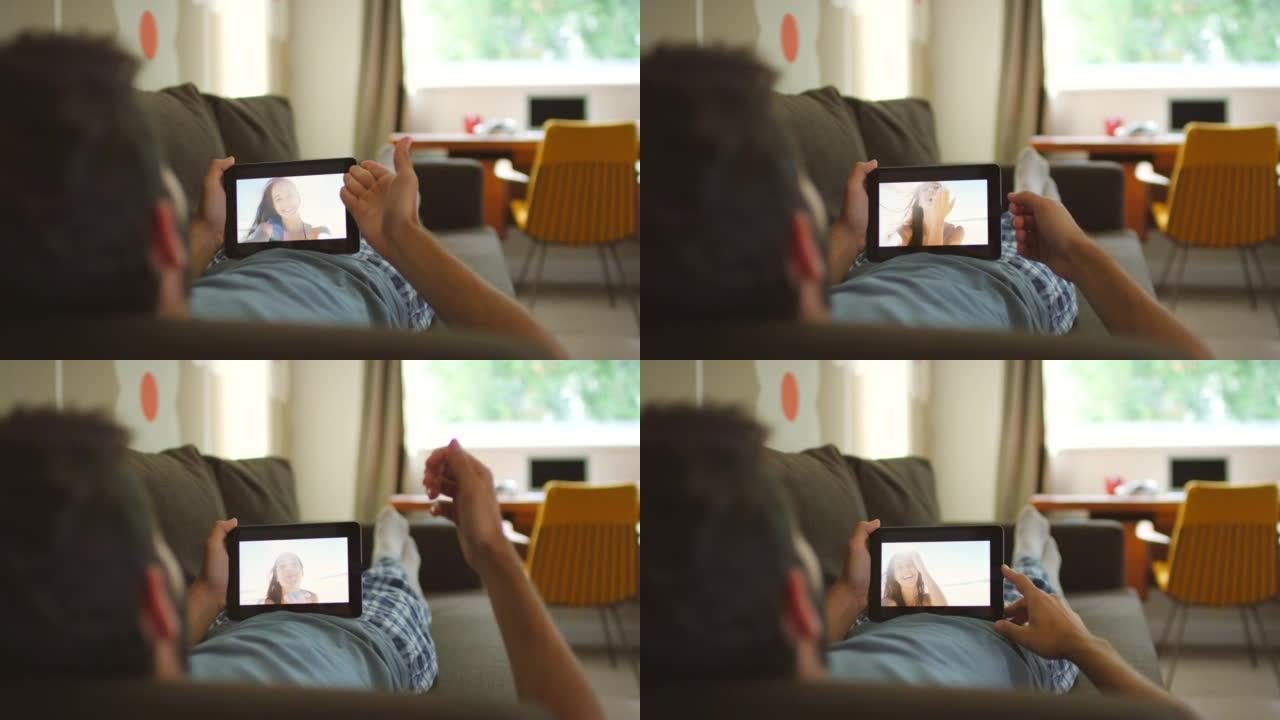 4k视频片段，一名男子使用数字平板电脑在沙发上放松，进行视频通话