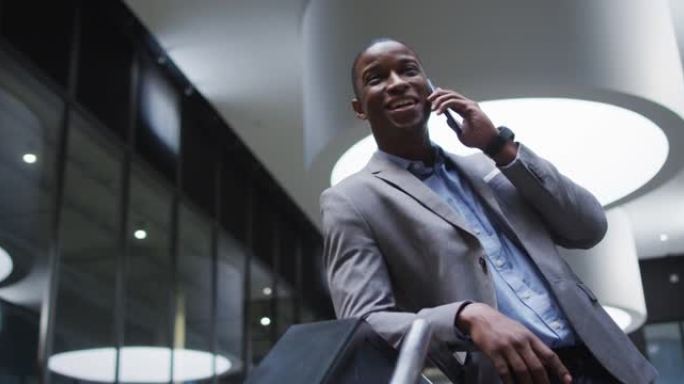 在现代办公室的大厅中使用智能手机的非洲裔美国商人