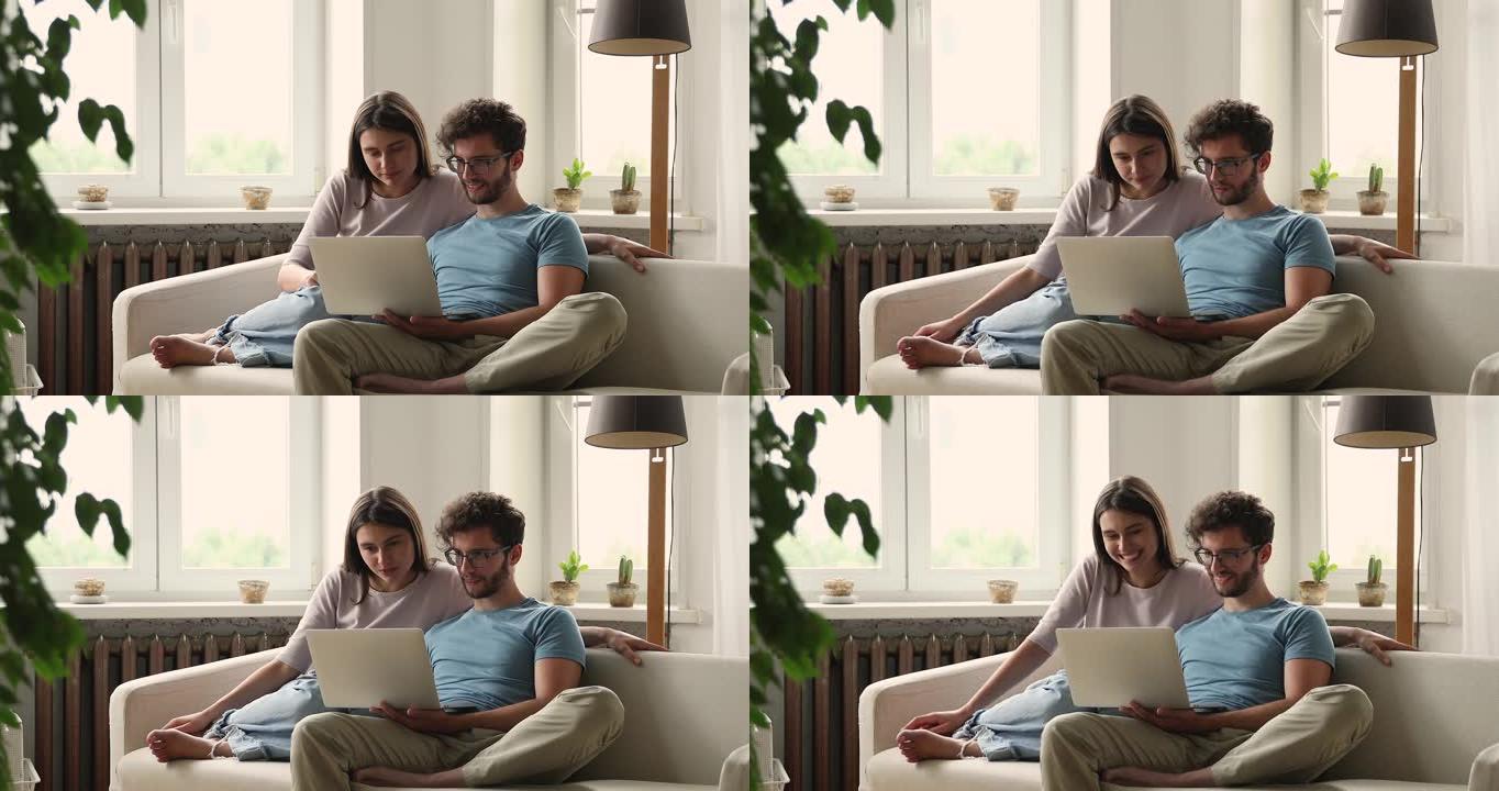 可爱的年轻妻子看着丈夫在笔记本电脑上玩电脑游戏