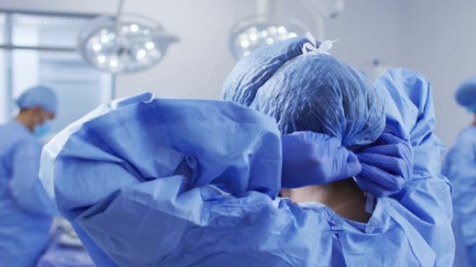 混血女外科医生穿着防护服站在手术室