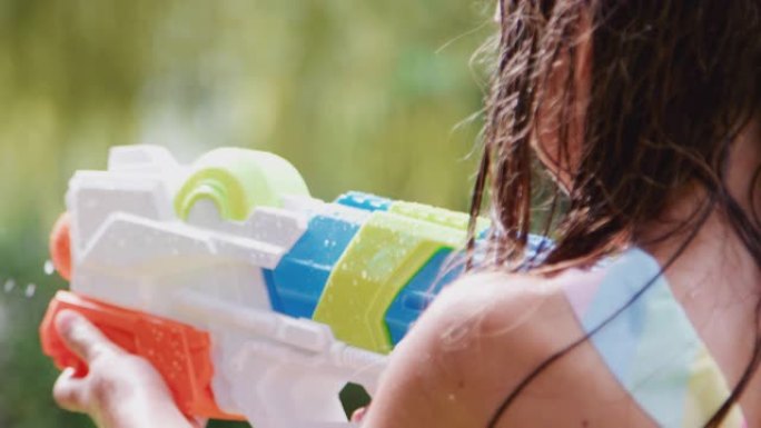 穿着游泳衣的女孩在夏季花园用水枪玩得开心
