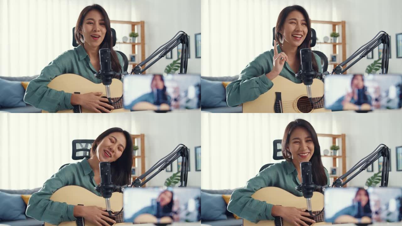 十几岁的亚洲女孩影响者玩吉他音乐使用麦克风记录和智能手机在线观众在家收听。