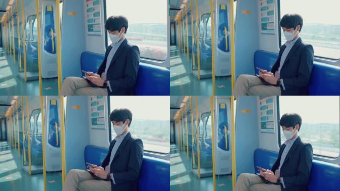 戴着医用口罩的电动火车上的人玩智能手机。