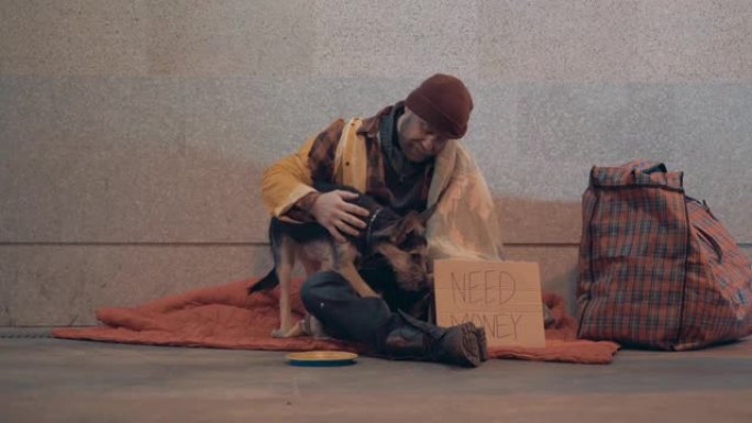 一个无家可归的人和他的狗在地下通道要钱