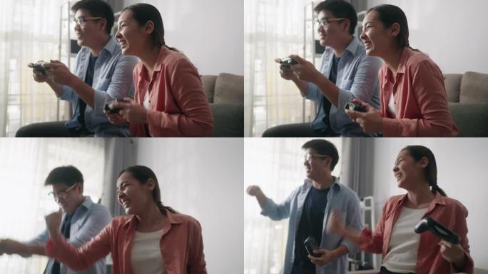 快乐的亚洲夫妇坐在沙发上，在控制台上玩电子游戏