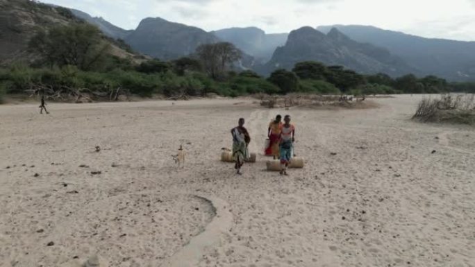 气候变化。干旱。水危机。特写侧视图。由于持续干旱，非洲妇女用塑料容器走路和滚水回家。肯尼亚
