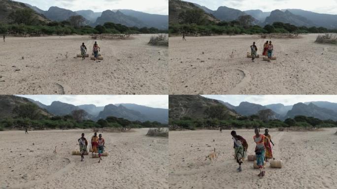 气候变化。干旱。水危机。特写侧视图。由于持续干旱，非洲妇女用塑料容器走路和滚水回家。肯尼亚