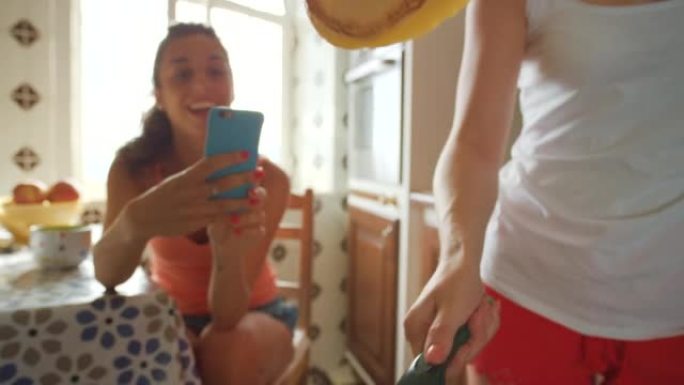 一个微笑的年轻女子在手机上播放她的朋友翻转煎饼的视频
