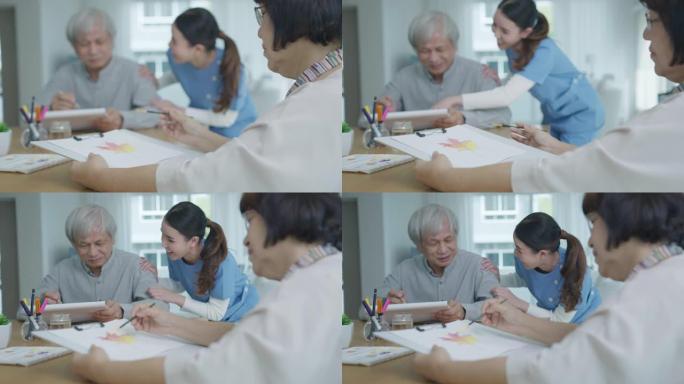 迷人的年轻亚洲公民夫妇坐在家里的水彩画艺术品桌子上，护士在精神卫生治疗或亚洲老年人检疫活动生活方式中