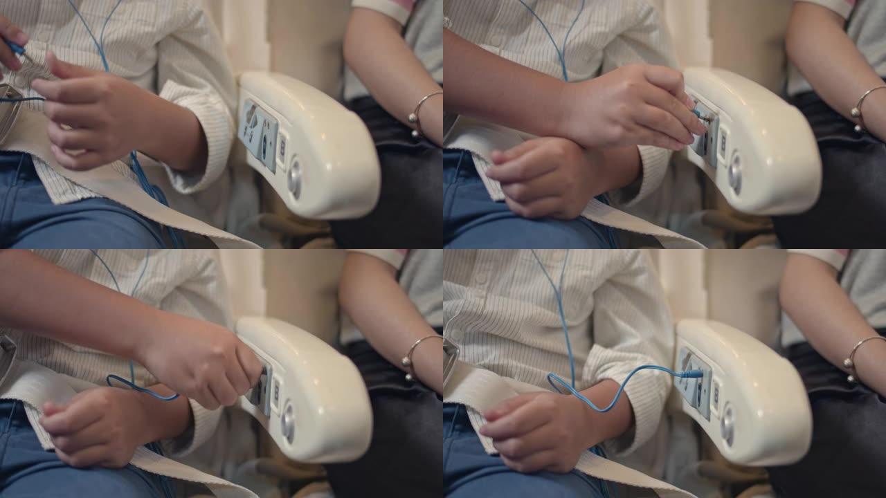 亚洲男孩插入耳机插孔，在飞机上听音乐。