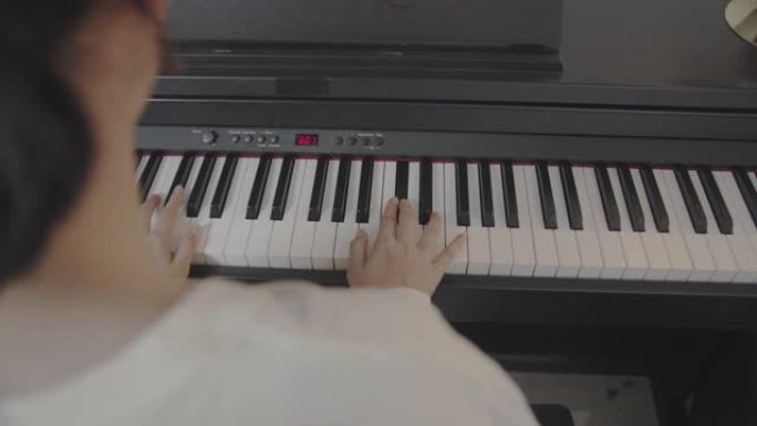 特写亚洲少年在家客厅弹键盘钢琴。美丽的女孩钢琴家在社交媒体上直播时弹钢琴。网络影响者Vlog或互联网