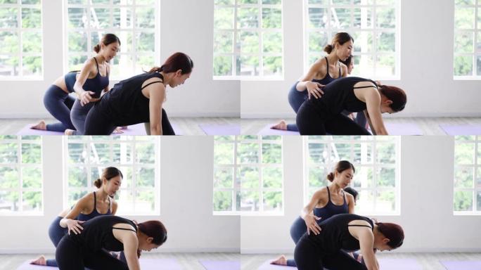 年轻的亚洲运动型有魅力的人与教练一起练习瑜伽课。