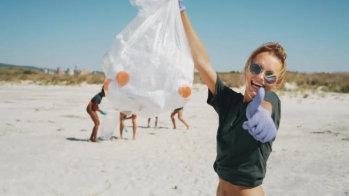 一位戴着墨镜的年轻金发女志愿者的慢动作在镜头前微笑着，对在大海的海滩上捡拾塑料垃圾以保护环境感到满意