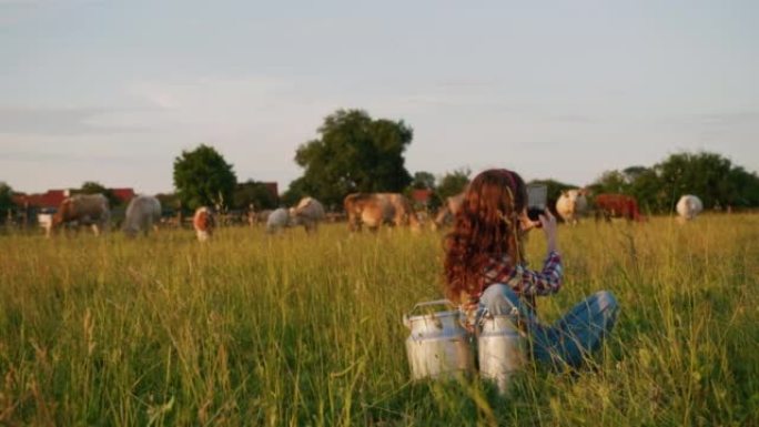 SLO MO年轻的女农民在牧场用智能手机拍照