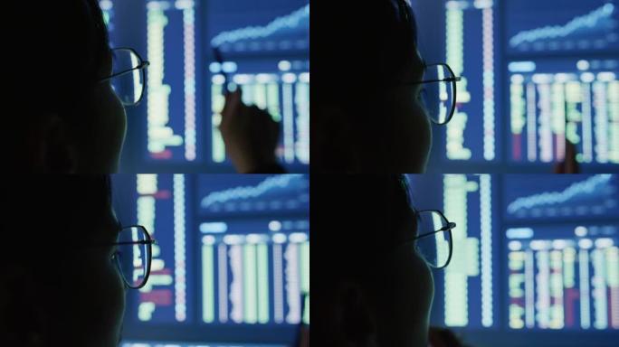 深夜在笔记本电脑前滚动眼镜的特写眼睛。编码员，她在数字交易所检查比特币价格图表