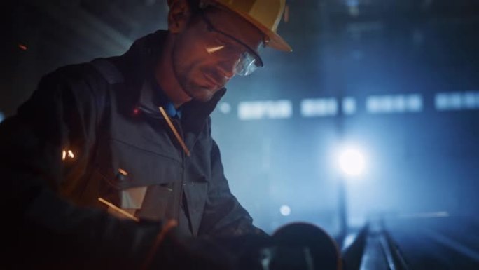 重工业工程工厂内部与工业工人使用角磨机和切割金属管。安全制服和安全帽制造金属结构的承包商。
