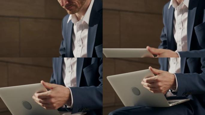 一名身穿深蓝色西装和白色衬衫的男子在灰色笔记本电脑上打印，而相机则将他从上到下拍摄。