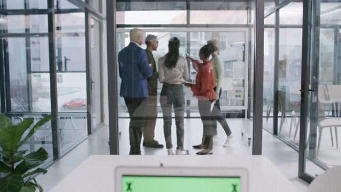 一群商人在办公室的玻璃墙上集思广益的4k视频片段，笔记本电脑在前景中显示绿色屏幕