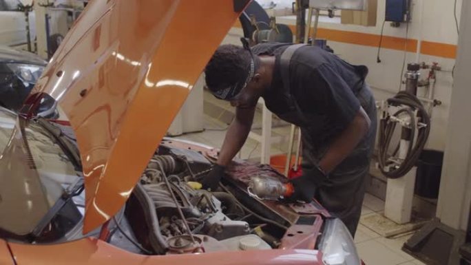 非裔美国机械师在汽车修理厂检查汽车零件