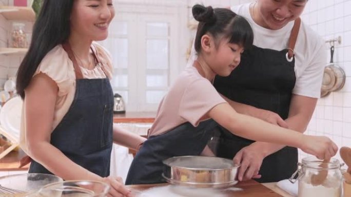 一个由父母和女儿组成的温暖家庭在厨房里烘烤并快乐地烘烤。它代表了一家人在一起的时间。