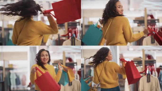 一个快乐的多民族女性带着购物袋在服装店微笑、跳舞和旋转的肖像。年轻的成年黑人女性顾客在百货商店购买时