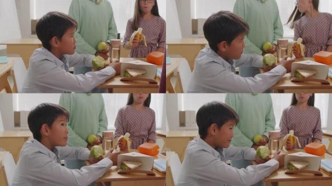 开朗的亚洲男孩在学校休息时吃苹果