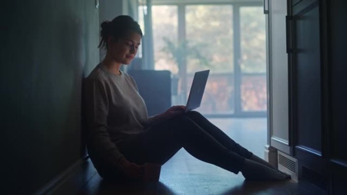 年轻女子在家使用笔记本电脑。坐在地板上的美丽女孩使用互联网，做远程工作，喝早晨的咖啡。丰富的生产工作